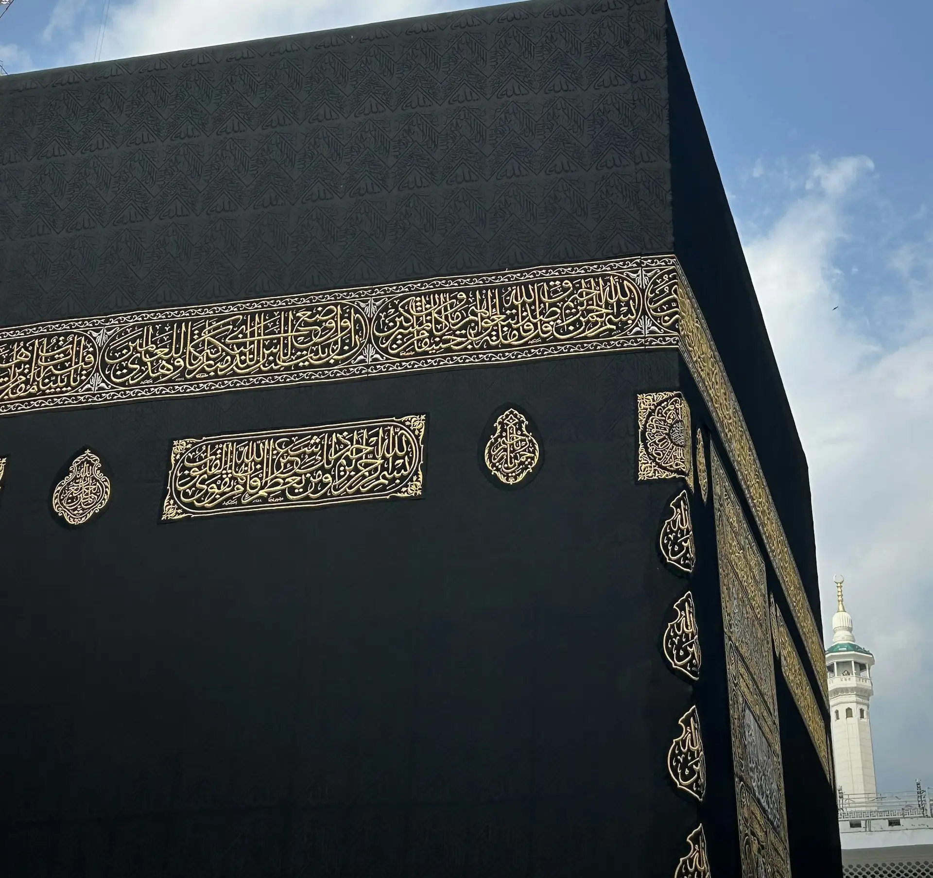The corner of the Kaaba, its gold-embroidered Kiswah against a clear sky
