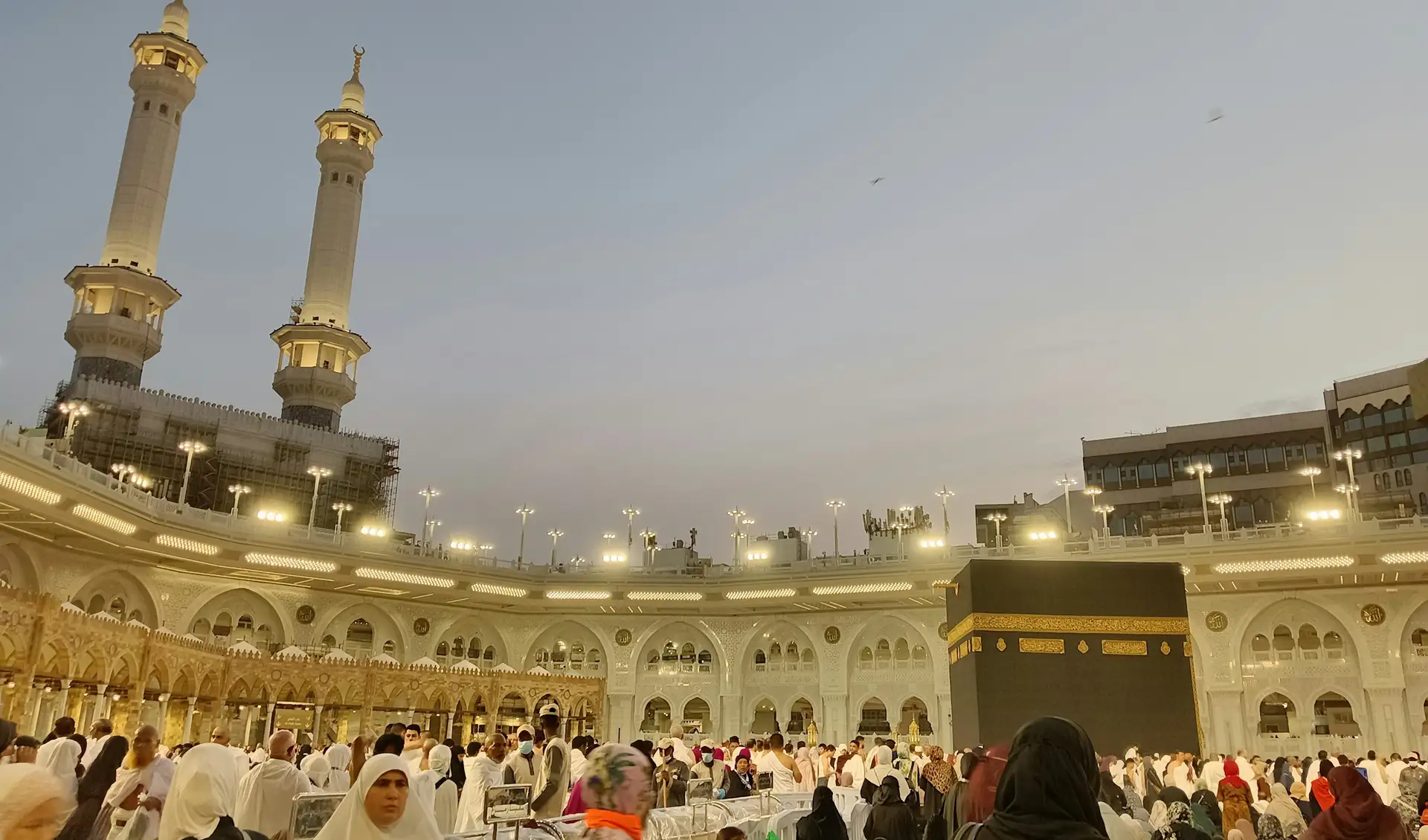 Pilgrims gathered around the Kaaba in Masjid al-Haram in warm evening light