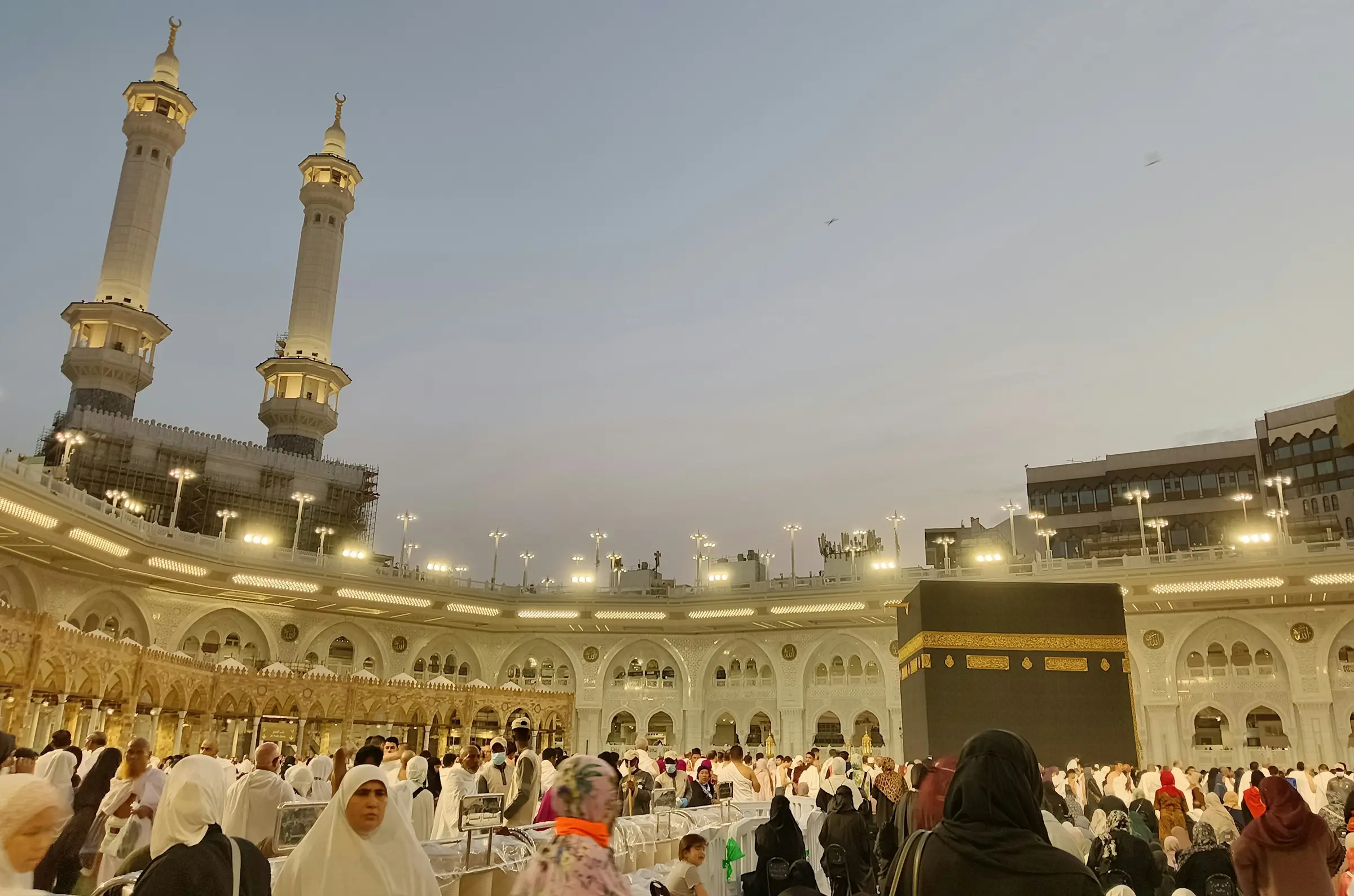 Pilgrims gathered around the Kaaba in Masjid al-Haram in warm evening light