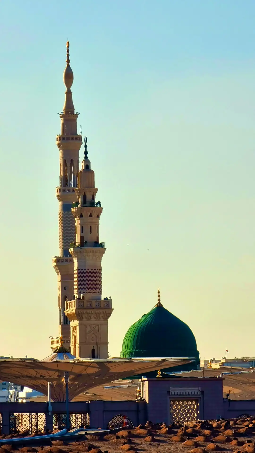 A minaret rising beside the Green Dome of the Prophet's Mosque in warm evening light