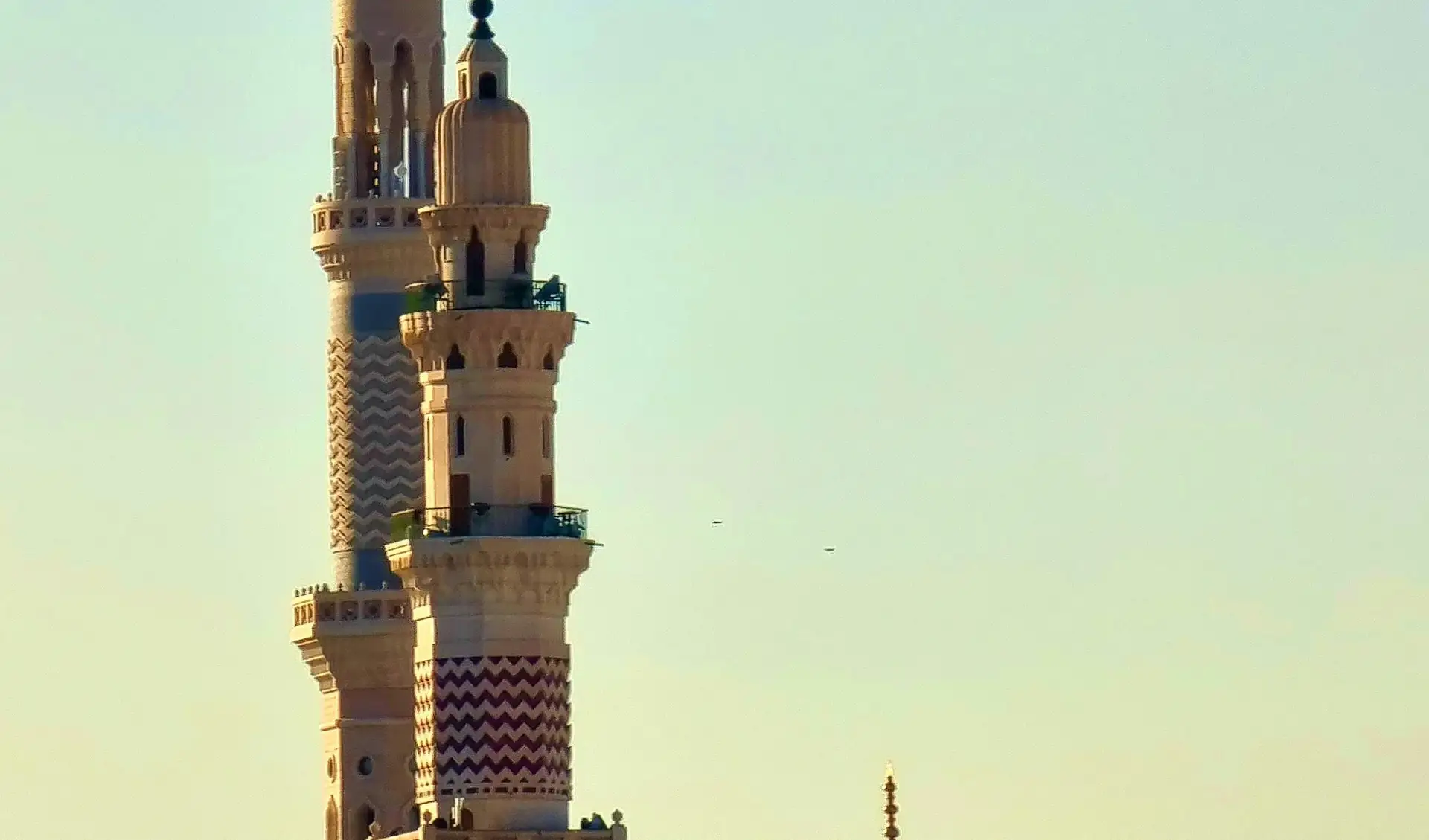 A minaret beside the Green Dome in warm evening light