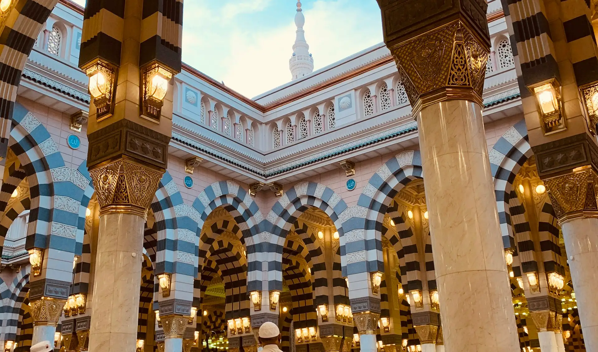 Striped arches and brass lanterns in the Prophet’s Mosque