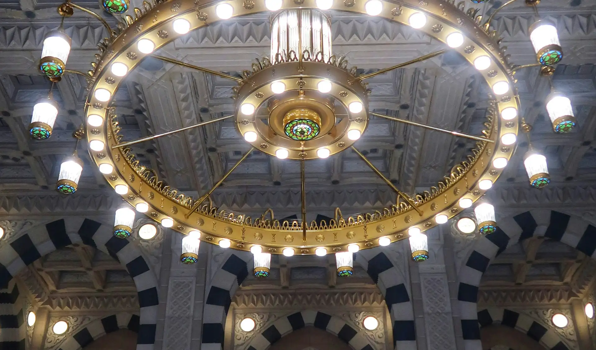 A brass chandelier beneath the painted domes of the Prophet’s Mosque