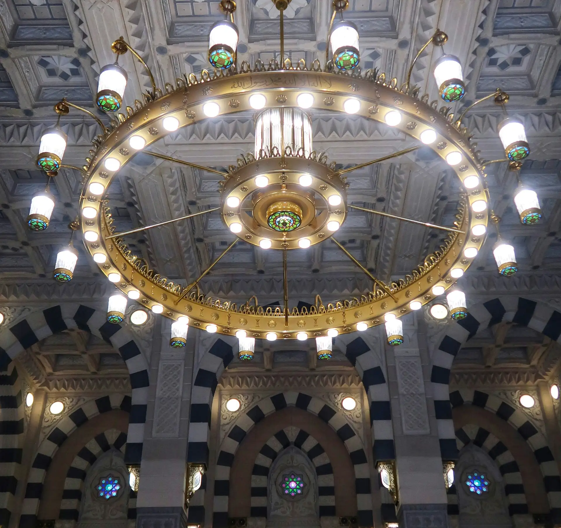 A brass chandelier beneath the painted domes of the Prophet’s Mosque