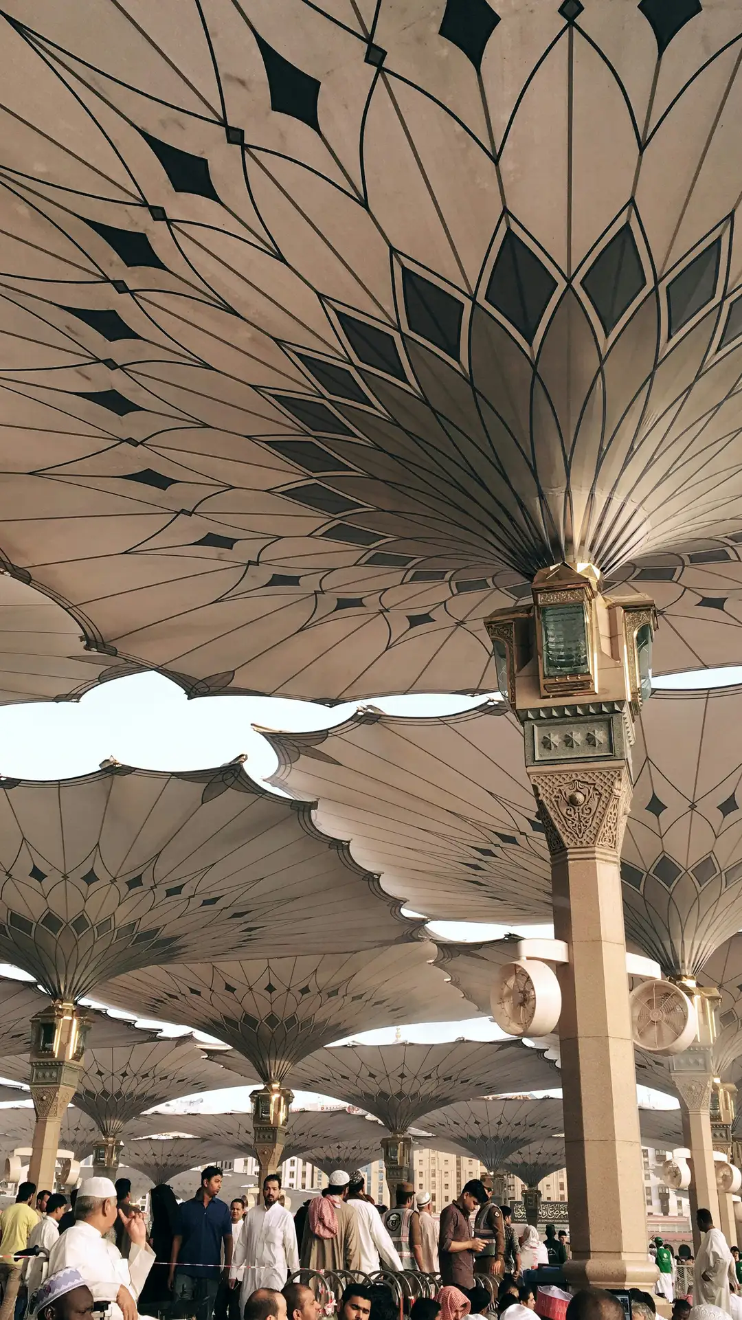 Pilgrims resting beneath the open shade umbrellas of the Prophet's Mosque