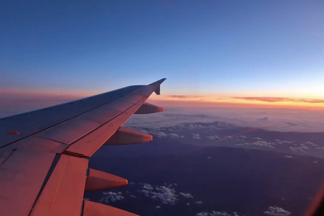 The wing of an airliner above cloud in low evening light